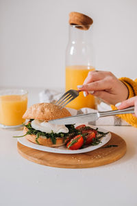 Breakfast sandwich with egg and arugula and cherry tomatoes on the table with orange juice	
