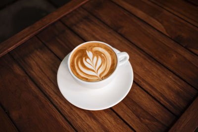 Latte art coffee on wooden table in coffee shop