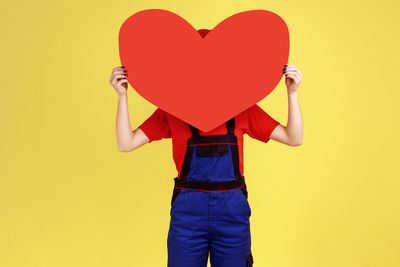 Midsection of man holding heart shape against blue background