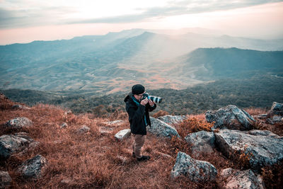 Man photographing on mountain against sky