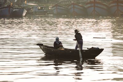 Silhouette people on boat in river