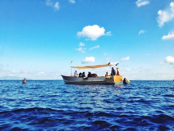 People on boat sailing in sea against sky