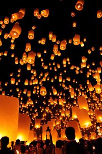 Low angle view of illuminated lanterns hanging against sky at night