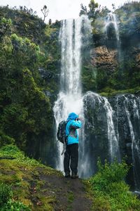 Hiker standing next to a waterfall at nithi waterfall, mount kenya national park, kenya