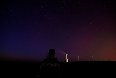 Rear view of man against sky at night