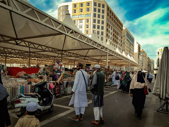 People walking on street in city against sky