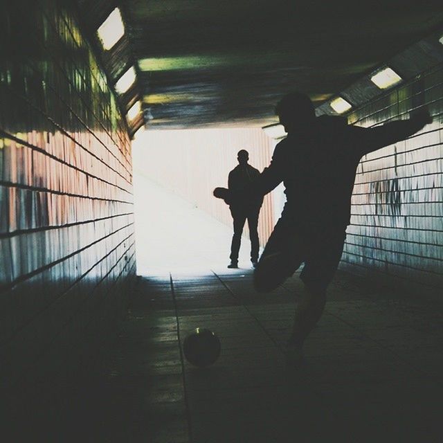 men, lifestyles, indoors, walking, silhouette, full length, leisure activity, person, rear view, architecture, built structure, shadow, sunlight, on the move, city life, unrecognizable person, standing