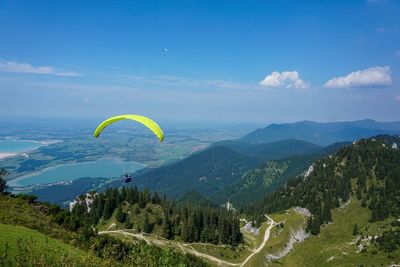 Person paragliding over mountain against sky