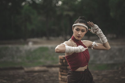 Thoughtful young woman practicing martial arts against trees