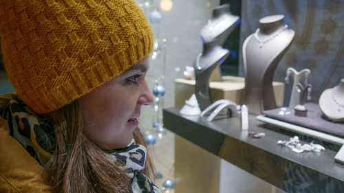 Close-up side view of young woman wearing warm clothing while shopping in jewelry store