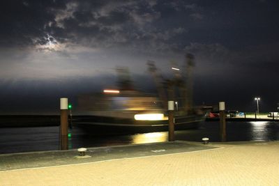 Illuminated street light against sky at night