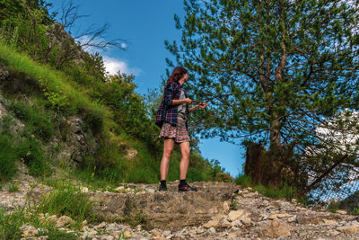 Woman standing by tree against sky