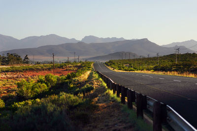 Scenic view of road by mountains against clear sky