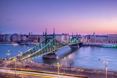 Illuminated liberty bridge over danube river against sky at night