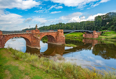 Arch bridge over river against sky