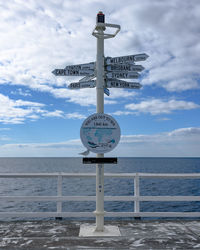 Information sign by sea against sky