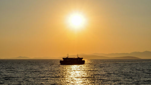 Boat sailing in sea against sky during sunset