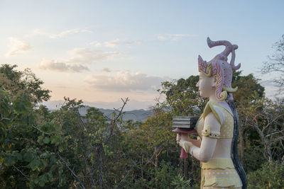 Statue against trees and plants against sky