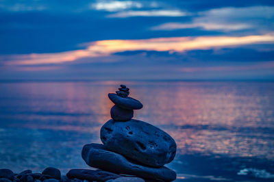 Close-up of pebbles on beach against sky during sunset