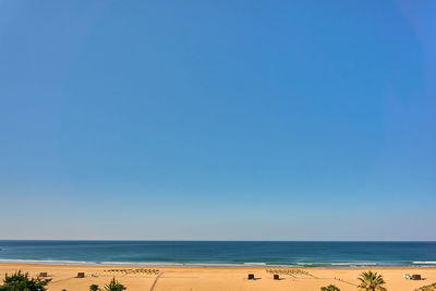 Scenic view of beach against clear blue sky