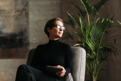 Portrait of young woman sitting against wall