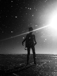 Silhouette woman standing on beach against sky at night