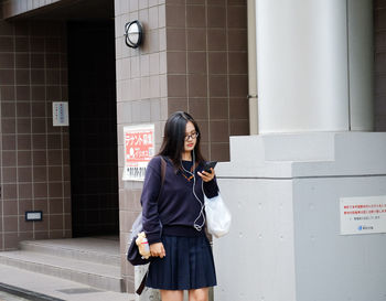 Young woman using mobile phone in city