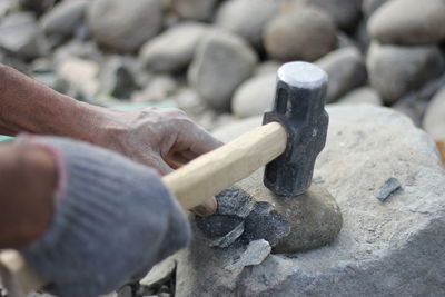 Cropped hands breaking stone with hammer
