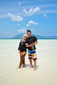 Full length of friends standing on beach against sky