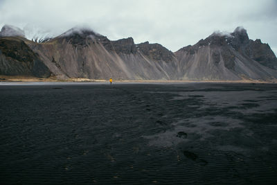 Man walking on land against mountains and sky