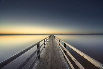 Pier over lake against sky during sunset