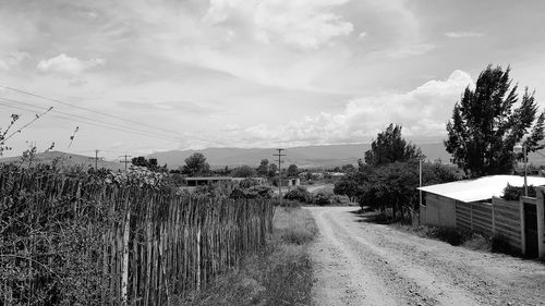 Road amidst trees on field against sky