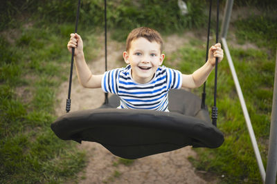 Portrait of boy swinging at playground