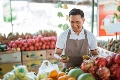 Portrait of man holding fruits at market stall