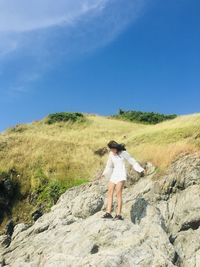 Full length of man standing on rock against sky