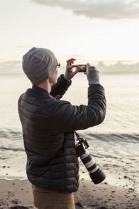 Hiker photographing through smart phone at beach