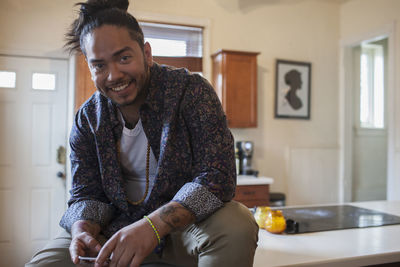 Young man sitting on a kitchen bench.