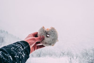 Close-up of hand holding ice cream against sky