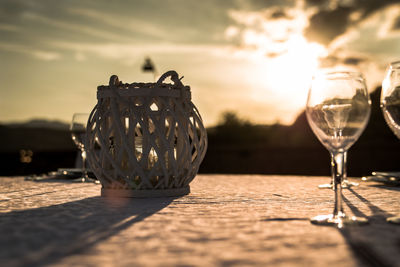 Close-up of wineglass on table against sky during sunset