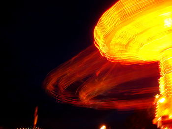 Low angle view of illuminated lighting equipment against black background