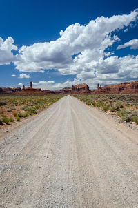 Dirt road amidst landscape against sky