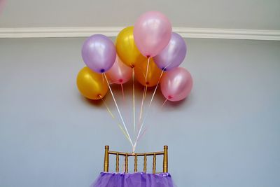 Colorful balloons on chair against wall