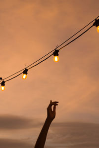 Low angle view of illuminated light bulb against sky during sunset