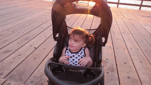 Girl sitting in baby carriage on deck