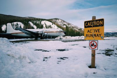 Information sign on snow against sky during winter