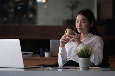 Mid adult woman using mobile phone at table