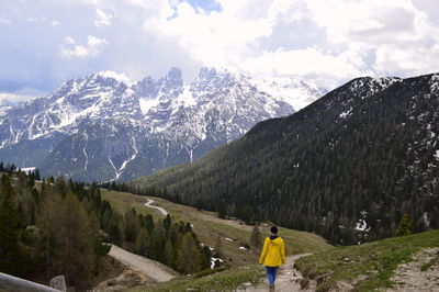 Rear view of person on snowcapped mountains against sky