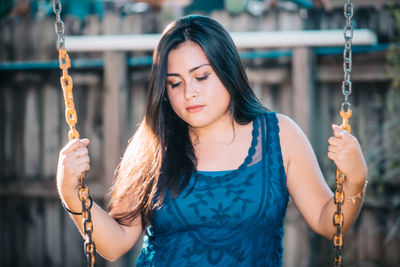 Close-up of young woman holding swing chain in playground