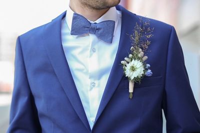 Midsection of groom wearing suit with boutonniere