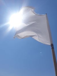 Low angle view of flag against blue sky on sunny day